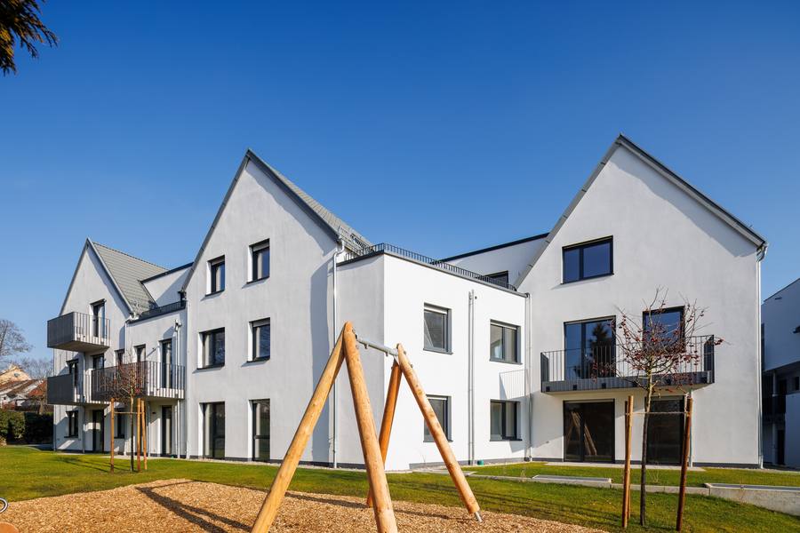 Hofseite von The Urban Terrace mit Balkonen, Rasenfläche und Spielplatz