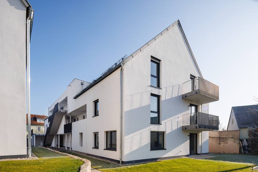 Giebelfassade mit anthrazitfarbenen Balkonen und Laubengang